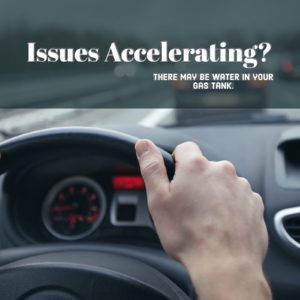 hand on car steering wheel with text that read "Issues accelerating? There may be water in your gas tank."
