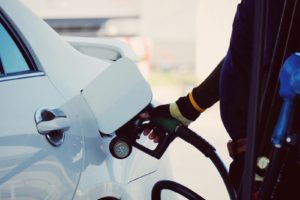 person filling up car with fuel hose at a gasoline station pump