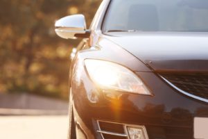 left side of a sedan with the headlight shining brightly