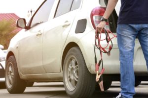 person retrieving jumper cables from the trunk of an SUV