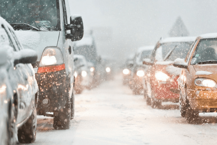 vehicles sitting in traffic during a snowfall