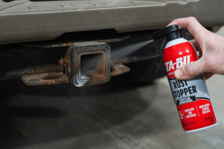 aerosol can spraying rusted area of a truck hitch