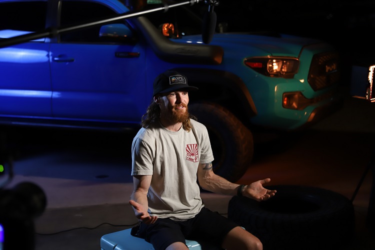 person sitting down in front of pickup truck for interview