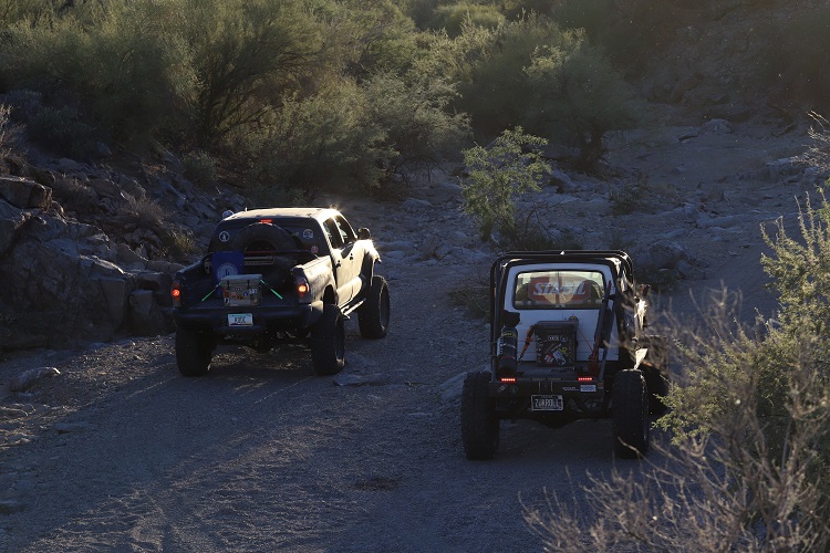 two off-roading vehicles driving side by side in desert