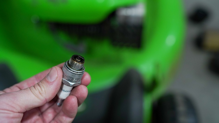 person holding lawn mower spark plug close