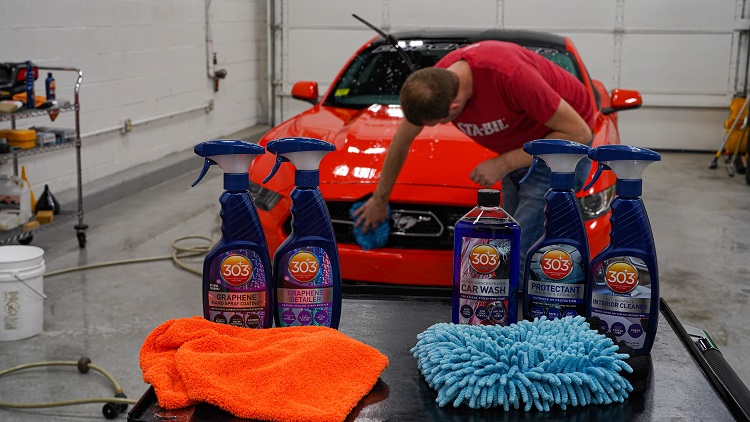 person cleaning car grille with a bench of 303 cleaning products in view