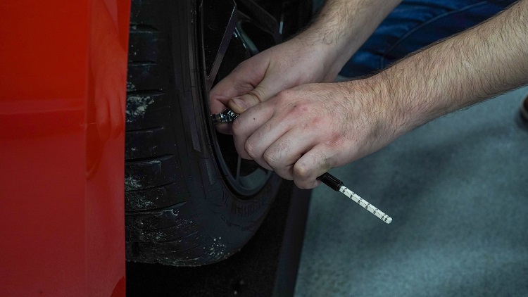 person checking tire pressure with device in hand