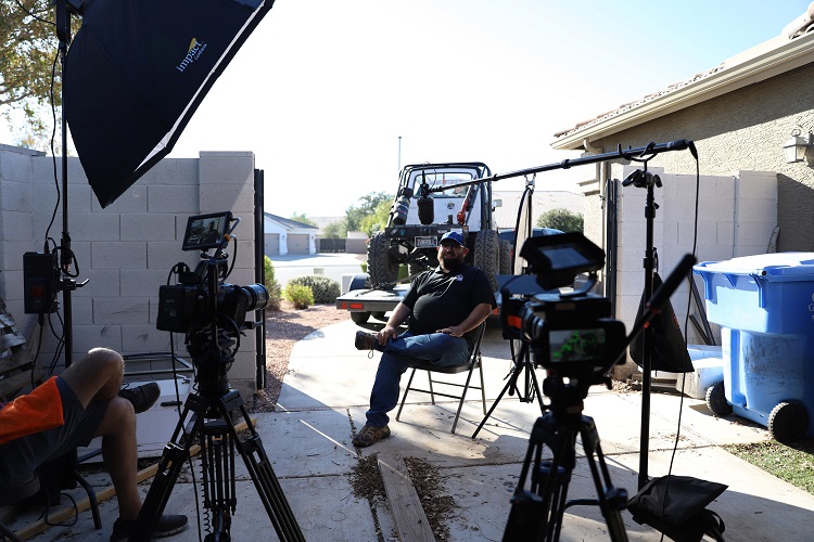 two people sitting in charis across from each other with cameras and equipment setup