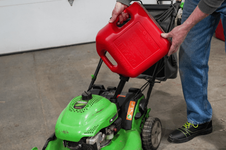 person pouring gasoline into a lawn mower's fuel reserve