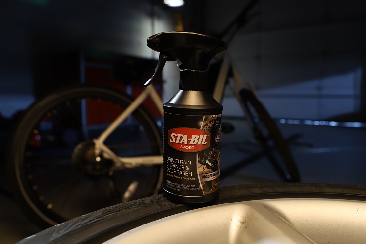 bottle of STA-BIL SPORT Bike Drivetrain Cleaner and Degreaser in front of bicycle