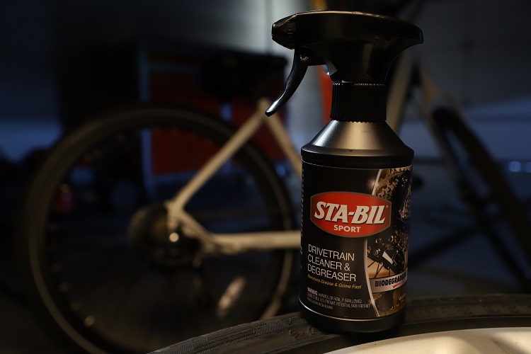 bottle of STA-BIL SPORT Bike Drivetrain Cleaner & Degreaser with bike in background