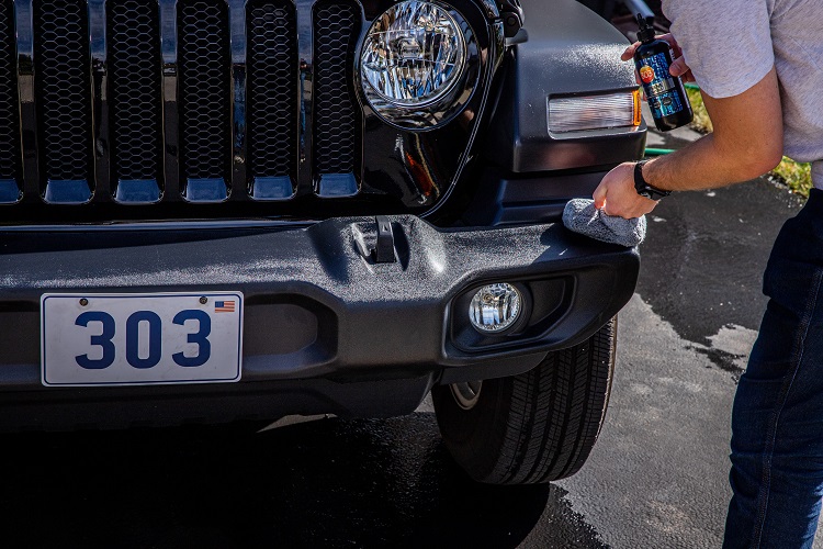 person using applicator on front bumper of Jeep Wrangler
