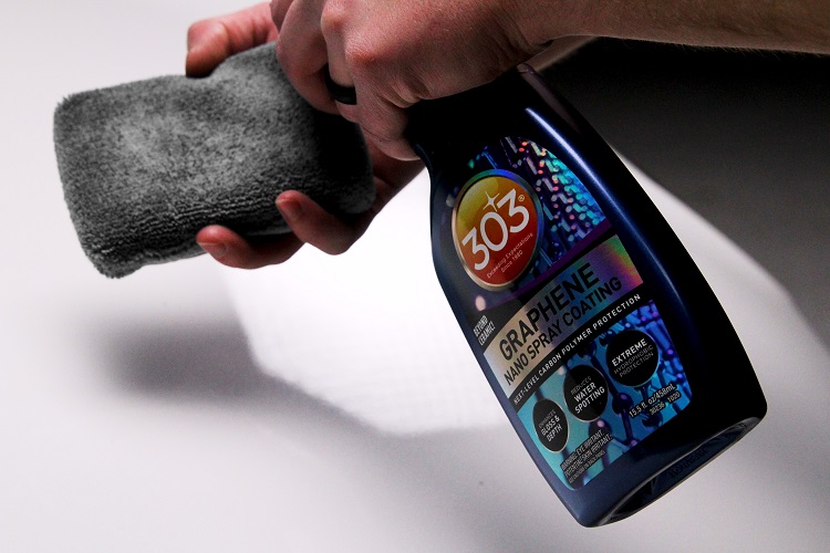 person spraying detailing product onto a microfiber applicator