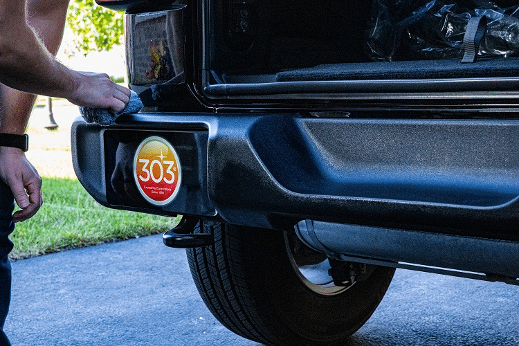 person detailing the front bumper of a car with a microfiber applicator