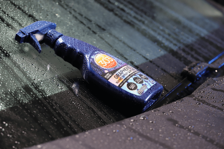 car detailing product on windshield with water beads surrounding it