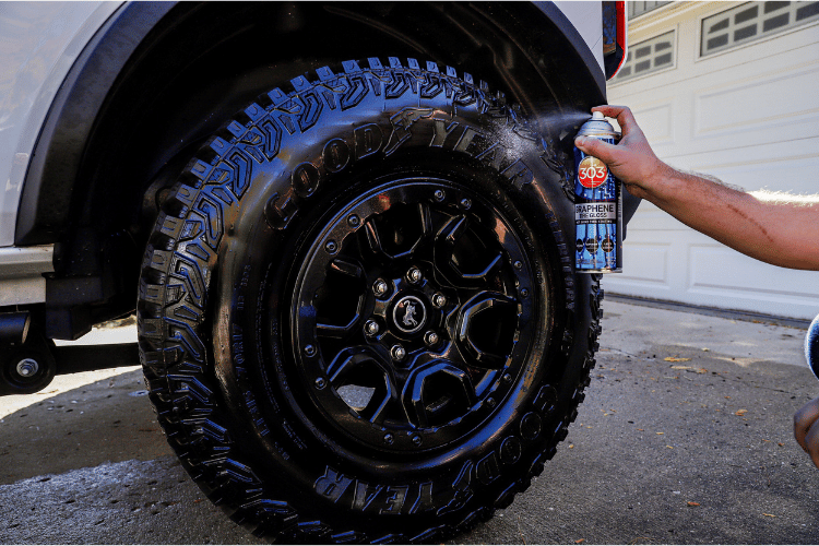 person applying aerosol product to a car tire